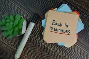 Back in 10 Minutes write on sticky notes isolated on Wooden Table. photo