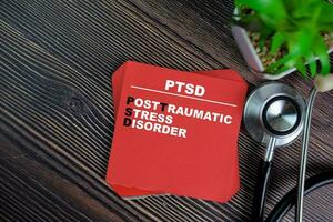 PTSD - Post Traumatic Stress Disorder write on sticky notes isolated on Wooden Table. medical concept photo