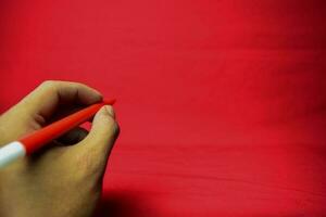 Man hand with red pen writing on red background photo