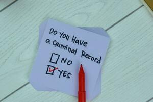 Concept of Yes, Do You Have a Criminal Record write on sticky notes isolated on Wooden Table. photo