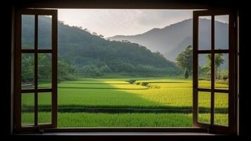 A window view of a rice field with mountains in the background. photo