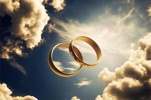 A pair of gold wedding rings floating in the sky. two wedding rings floating in the clouds with a sun in the background and a blue sky with clouds below them. . Wedding concept. photo