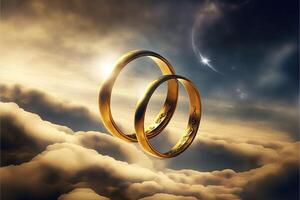 A pair of gold wedding rings floating in the sky. two wedding rings floating in the clouds with a sun in the background and a blue sky with clouds below them. . Wedding concept. photo