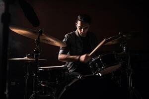 Musician plays drums, drummer on dark background. photo