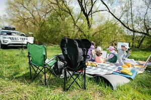 Happy young family, mother and children having fun and enjoying outdoor on picnic blanket painting at garden spring park, relaxation. photo