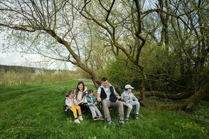 Family with three kids sitting on chairs at spring forest. photo