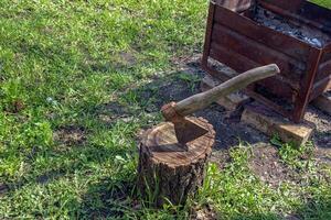 The wood chopper sticks out in wooden hemp. Ax and ax handle. Woodworking. Deforestation by a sharp axe. Ax to chop wood. Rusty but very sharp forester's ax or carpenter's axe. photo