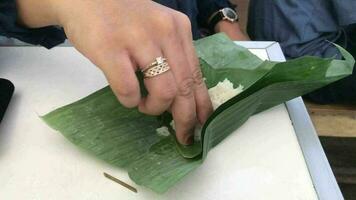 comiendo pegajoso arroz cinta plátano hojas por mano. video
