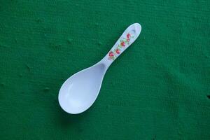 Photo of a white spoon with a green background