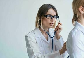 Professional doctor woman with stethoscope and female patient side view photo