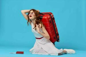 alegre mujer con rojo maleta sentado en el piso emociones aislado antecedentes foto