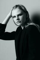 Aesthetic pensive sad blonde young model posing in classic jacket touching stocking hair at studio. Beautiful lady thoughtful looking and caress her curls. Black and White concept photo