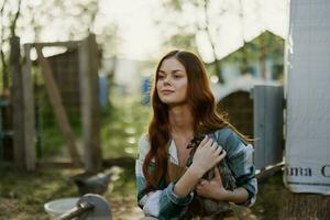 Young woman smiling for the camera holding a chicken and happy working on the farm photo