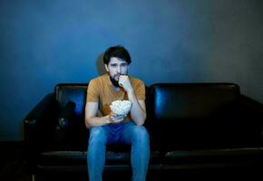 lonely man sitting on couch with popcorn plates gray wall photo