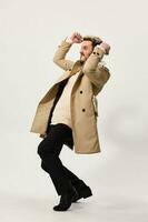 happy man in beige coat and fashionable trousers holds hands in fist success luck fun photo