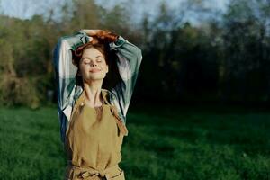 Portrait of a woman with a beautiful smile in her work clothes and apron in nature, enjoying relaxation after work in the sunset sunlight photo