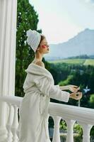 Portrait woman in a robe stands on an open balcony looking on the view photo