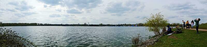 Low Angle View of Willen Lake Park with Local and Tourist Public Enjoying the Beauty of Lake and Park by Walking Around with Their Families. Footage Was Captured on 09-April-2023 at Milton Keynes UK photo