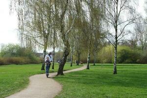 Low Angle View of Willen Lake Park with Local and Tourist Public Enjoying the Beauty of Lake and Park by Walking Around with Their Families. Footage Was Captured on 09-April-2023 at Milton Keynes UK photo