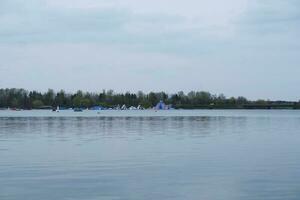 Low Angle View of Willen Lake Park with Local and Tourist Public Enjoying the Beauty of Lake and Park by Walking Around with Their Families. Footage Was Captured on 09-April-2023 at Milton Keynes UK photo