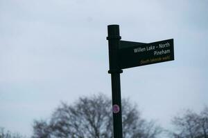 Low Angle View of Willen Lake Park with Local and Tourist Public Enjoying the Beauty of Lake and Park by Walking Around with Their Families. Footage Was Captured on 09-April-2023 at Milton Keynes UK photo