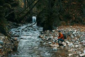 woman with backpack and autumn landscape mountains forest clear water river photo