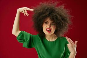 Beautiful fashionable girl Afro hairstyle green dress emotions close-up red background unaltered photo