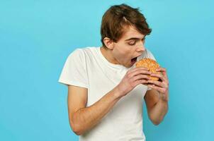 hombre comiendo hamburguesa en blanco camiseta dieta comida estilo de vida azul antecedentes foto