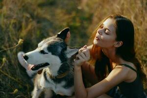 mujer sentado en campo con perro tejonero perro sonriente mientras gasto hora al aire libre con perro amigo foto