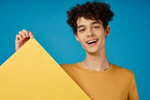 Cheerful guy with curly hair yellow poster mockup blue background photo