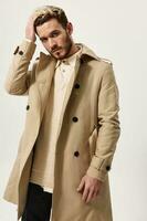 a bearded man in a beige coat straightens the hair on his head photo