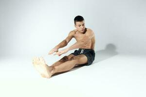 man doing sports exercises while sitting on the floor indoors photo