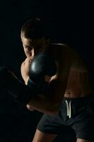 boxer in gloves on a black background bent down cropped photo