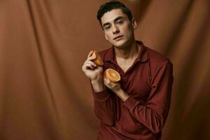 handsome man fashionable hairstyle oranges in hands red shirt studio attractive look photo