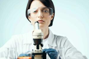 female laboratory assistant in a white coat with a microscope in the hands of a professional medicine technology photo