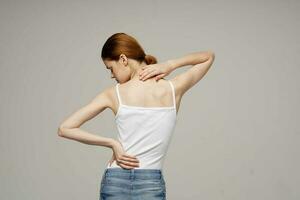 woman in white t-shirt back pain health problems osteoporosis studio treatment photo