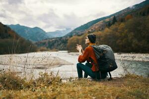 woman with backpack by the river mountain landscape autumn dry grass model photo