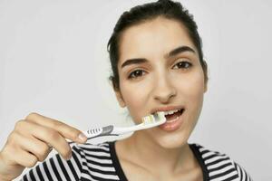 morena en un a rayas camiseta cepillo de dientes en mano aislado antecedentes foto