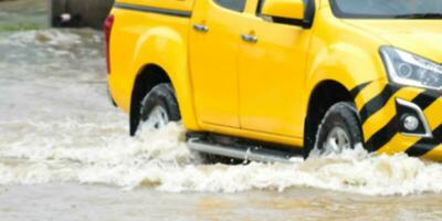 de cerca ver de el posterior rueda de un negro recoger camión ese estaba paso mediante un inundación, coche seguro y coche fijación concepto. foto