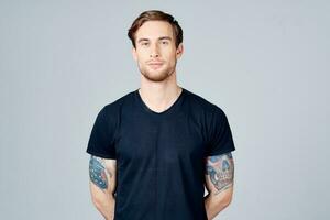 portrait of a man in a blue t-shirt with a tattoo on his arm blonde hair gray background photo