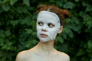 Beautiful woman cosmetic mask rejuvenation bushes in the background photo