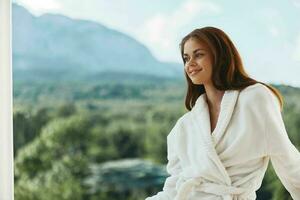 atractivo joven mujer blanco túnica admirar el ver desde el ventana montaña ver foto