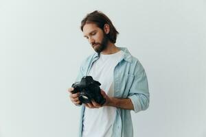 hombre hipster fotógrafo en un estudio en un blanco antecedentes mirando a el cámara pantalla y ajuste eso arriba para un foto disparar