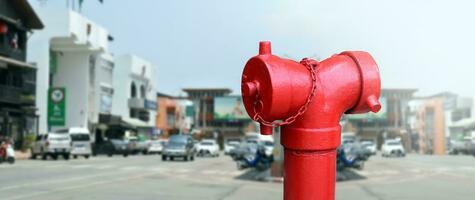 Red vintage fire extinguisher for firefighters installed by the road in the rural city in southeast asian country. photo