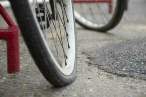 Closeup view of vintage bike which has flat wheels and parked on cement floor of street near the building, soft focus. photo