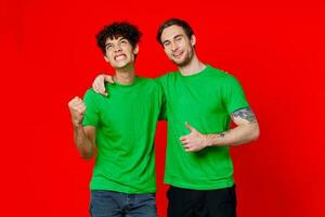 Two man green t-shirts embrace emotions friendship red background photo