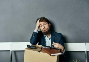 A man in a suit sits on a chair with a box job search depression photo