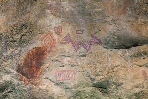 Prehistoric paintings on rock known as petroglyphs in Colombia photo