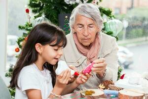 Grandmother teaching her granddaughter how to make christmas Nativity crafts - Real family photo