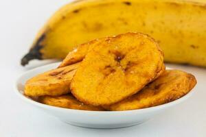 Fried half ripe plantain slices isolated on white background photo